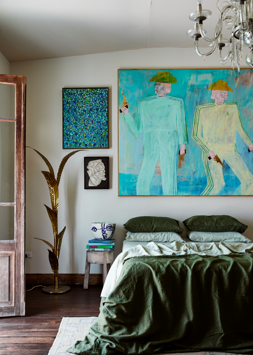 green and blue bedroom styled with linen sheets and artworks