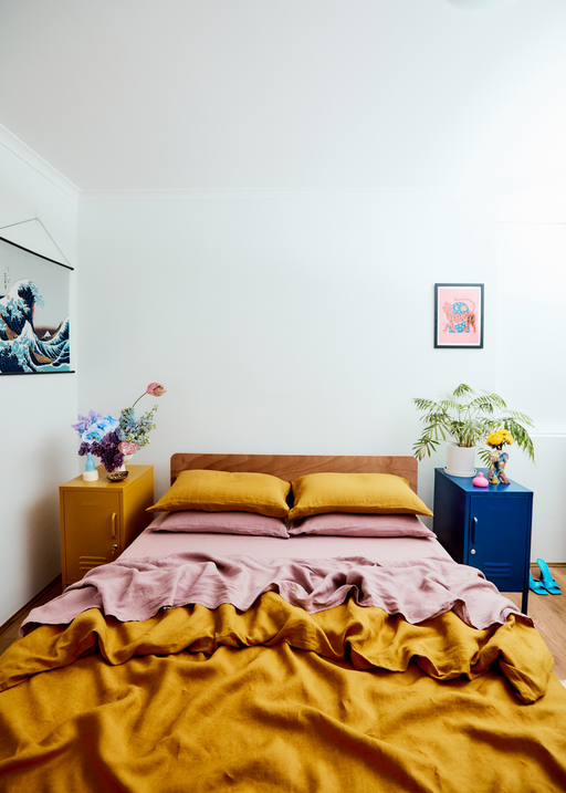 colourful bedroom with artworks and turmeric and lavender linen bed sheets